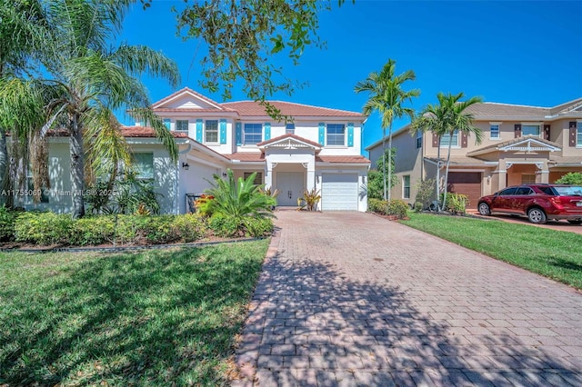 view of front of property featuring stucco siding, a tile roof, an attached garage, decorative driveway, and a front yard