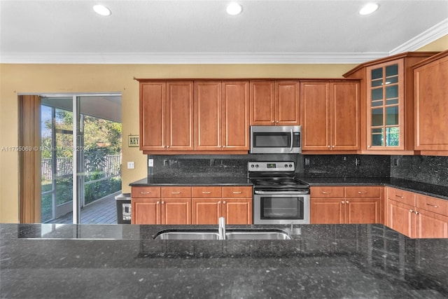 kitchen featuring tasteful backsplash, appliances with stainless steel finishes, ornamental molding, dark stone countertops, and a sink