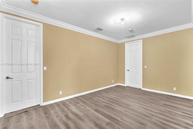 unfurnished room featuring visible vents, crown molding, and wood finished floors