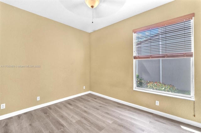 spare room with a ceiling fan, plenty of natural light, baseboards, and wood finished floors