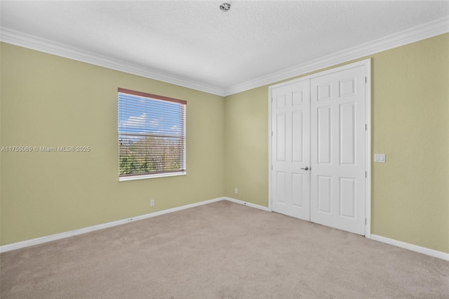 unfurnished bedroom with baseboards, a closet, carpet, and crown molding