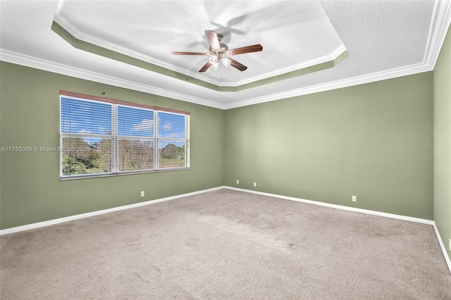 carpeted empty room with ornamental molding, a raised ceiling, a ceiling fan, and baseboards