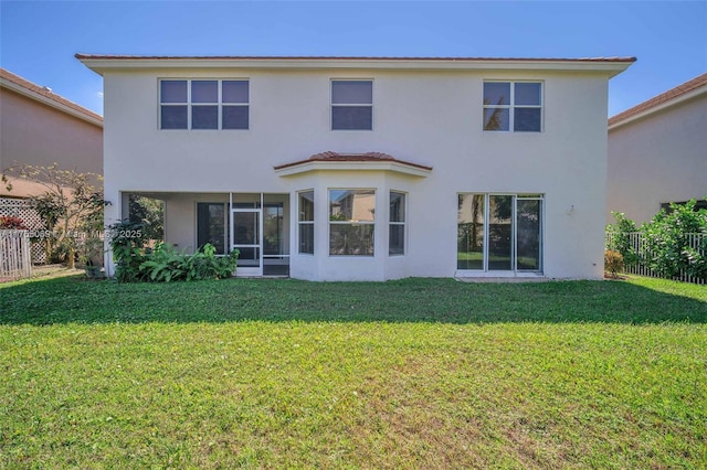 back of house featuring a yard, fence, and stucco siding