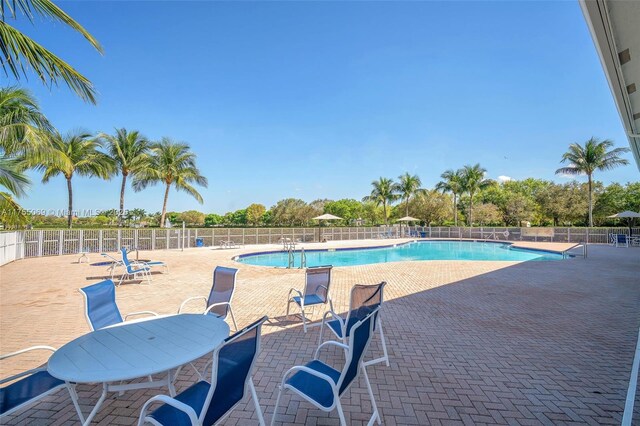 pool with a patio area and fence