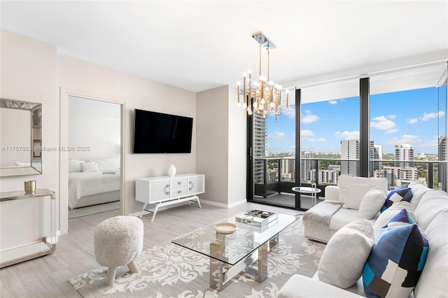 living area with baseboards, expansive windows, wood finished floors, and an inviting chandelier