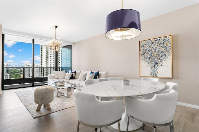 dining area featuring baseboards, wood finished floors, an inviting chandelier, expansive windows, and a view of city