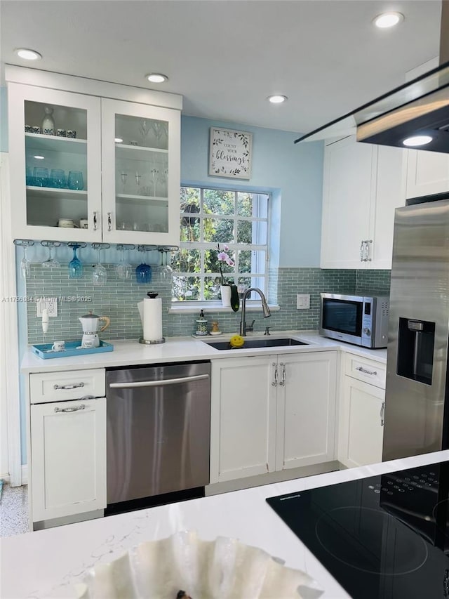 kitchen with a sink, white cabinets, light countertops, appliances with stainless steel finishes, and glass insert cabinets