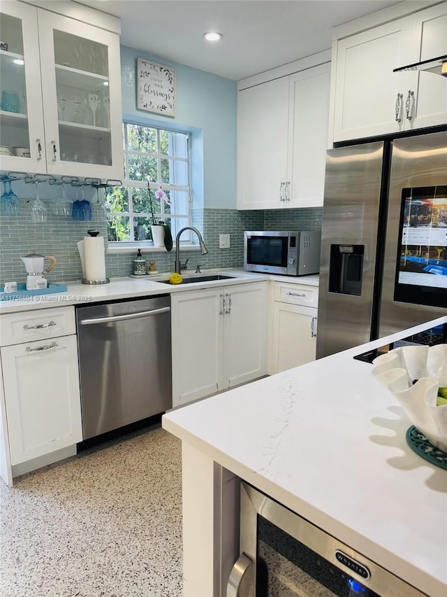 kitchen featuring stainless steel appliances, light countertops, white cabinetry, and a sink