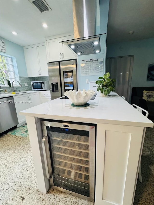 kitchen with beverage cooler, visible vents, island range hood, appliances with stainless steel finishes, and white cabinetry