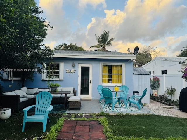 rear view of property featuring an outbuilding, a patio, stucco siding, outdoor lounge area, and fence