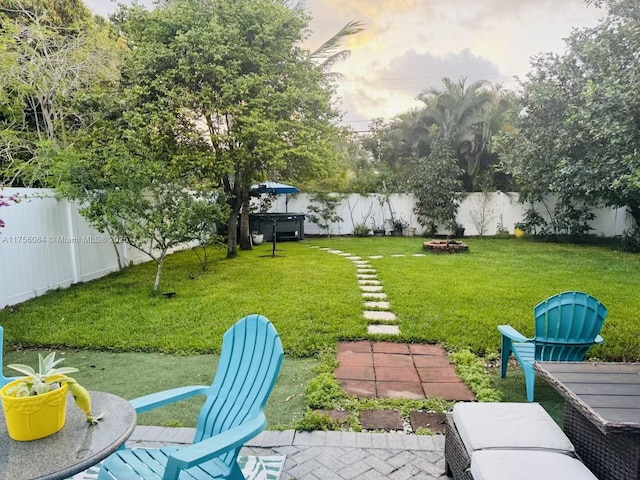 view of yard featuring a hot tub, a fenced backyard, a patio, and a fire pit