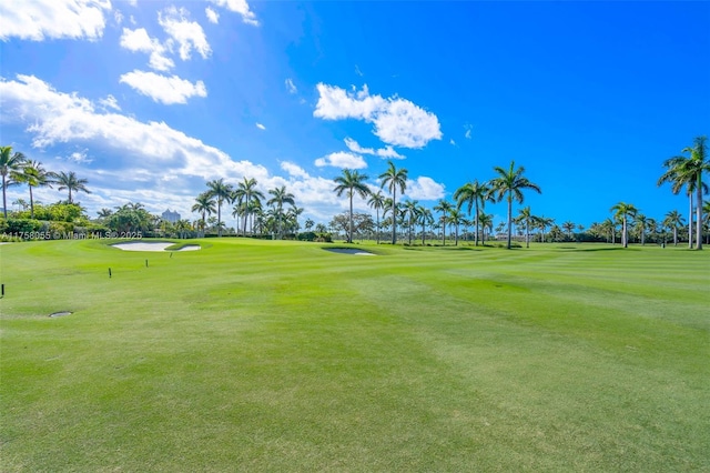 view of property's community with view of golf course and a lawn