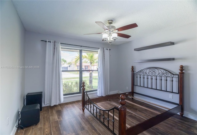 bedroom featuring a ceiling fan, a textured ceiling, baseboards, and wood finished floors