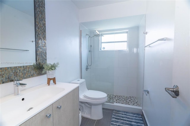 full bath featuring a stall shower, vanity, toilet, and decorative backsplash