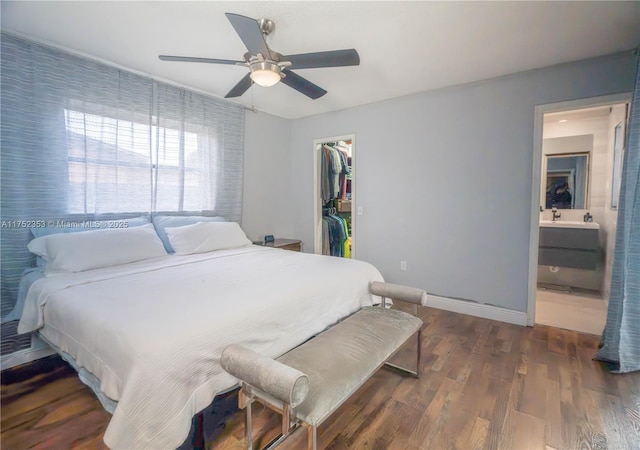 bedroom with a sink, wood finished floors, baseboards, a closet, and a walk in closet