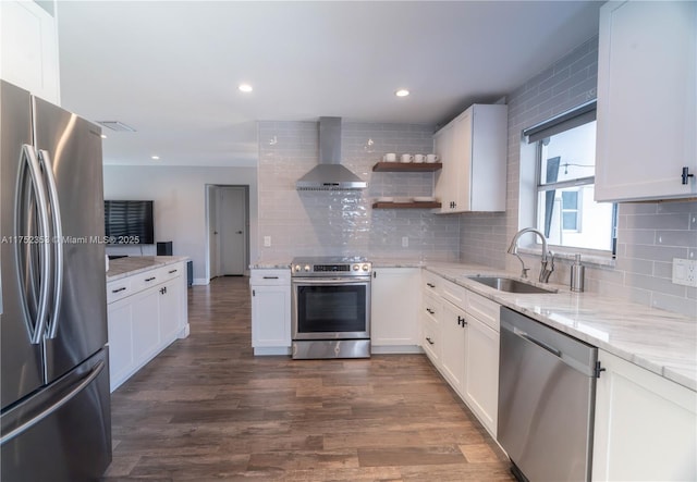 kitchen featuring dark wood finished floors, wall chimney exhaust hood, a sink, stainless steel appliances, and backsplash