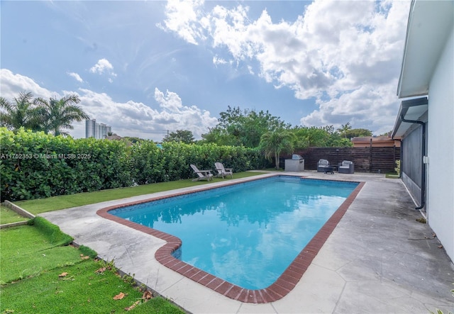 view of swimming pool featuring a fenced backyard, a fenced in pool, a lawn, and a patio