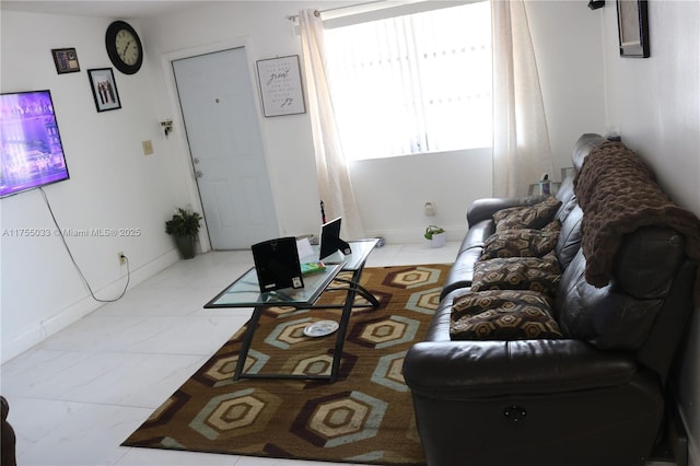 living area featuring marble finish floor and baseboards