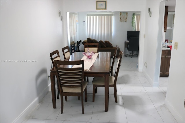 dining area featuring marble finish floor and baseboards