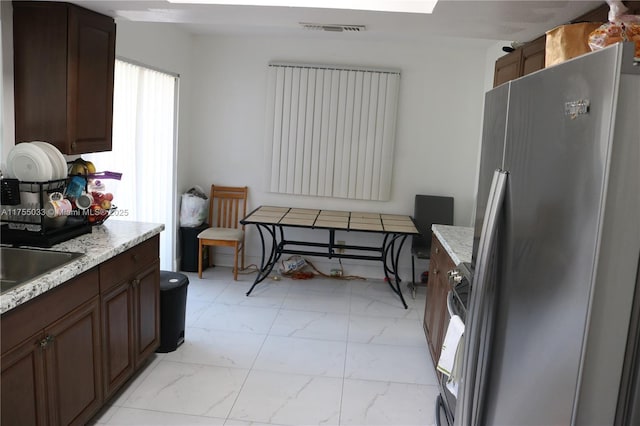 kitchen featuring marble finish floor, visible vents, a sink, and freestanding refrigerator