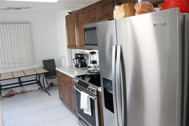 kitchen featuring brown cabinets, marble finish floor, visible vents, and stainless steel appliances