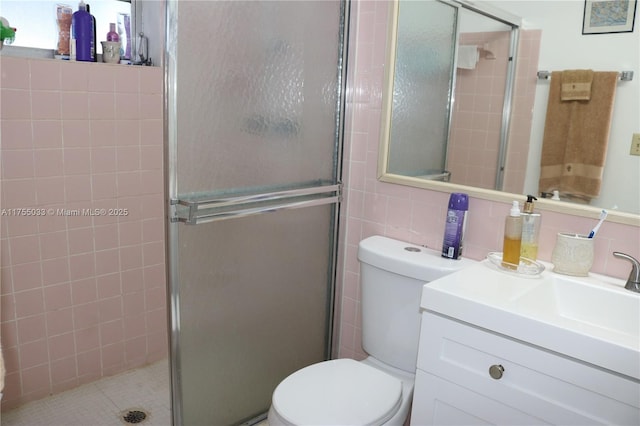 bathroom featuring tile walls, a shower stall, toilet, and vanity