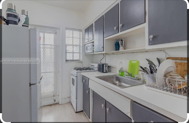 kitchen with open shelves, light countertops, a sink, light wood-type flooring, and white appliances