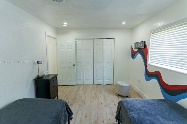 bedroom with light wood-style floors, baseboards, and a closet