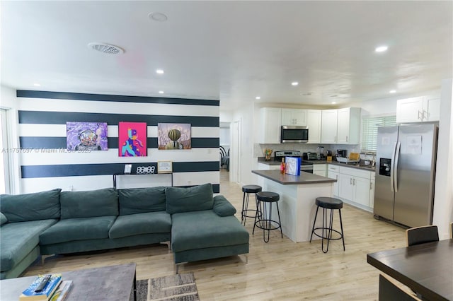 living room with light wood-style floors, visible vents, and recessed lighting