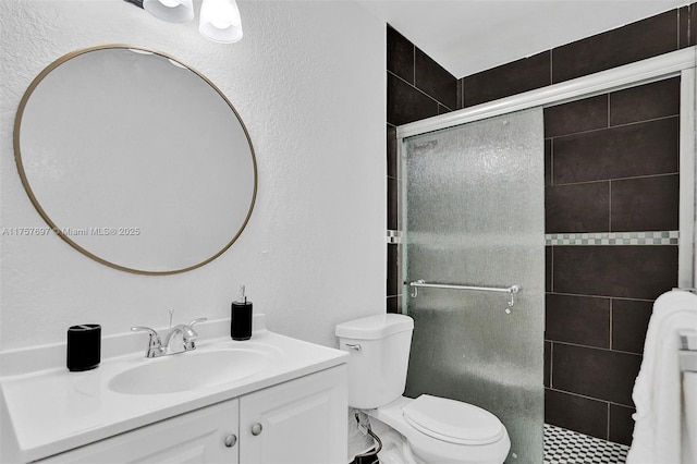 bathroom featuring toilet, a shower stall, and vanity