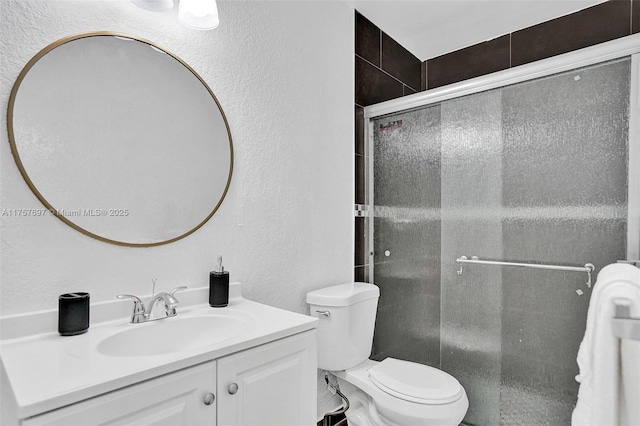 full bath with a stall shower, a textured wall, vanity, and toilet