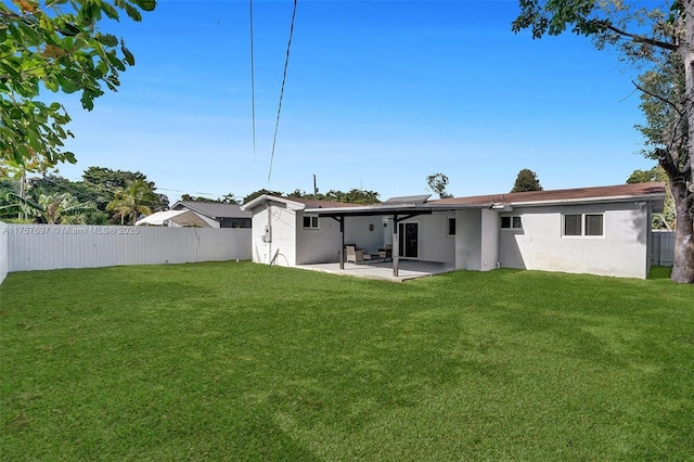 rear view of house featuring a yard, a patio area, a fenced backyard, and stucco siding