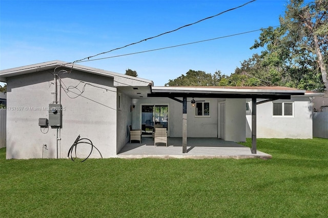 back of house featuring a patio, a lawn, and stucco siding