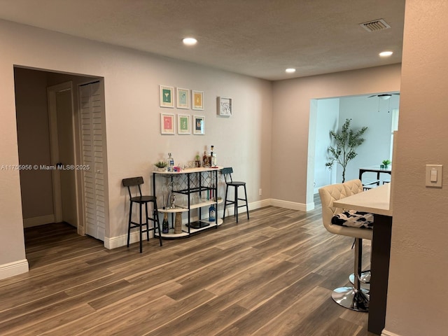 interior space with visible vents, baseboards, recessed lighting, wood finished floors, and a bar