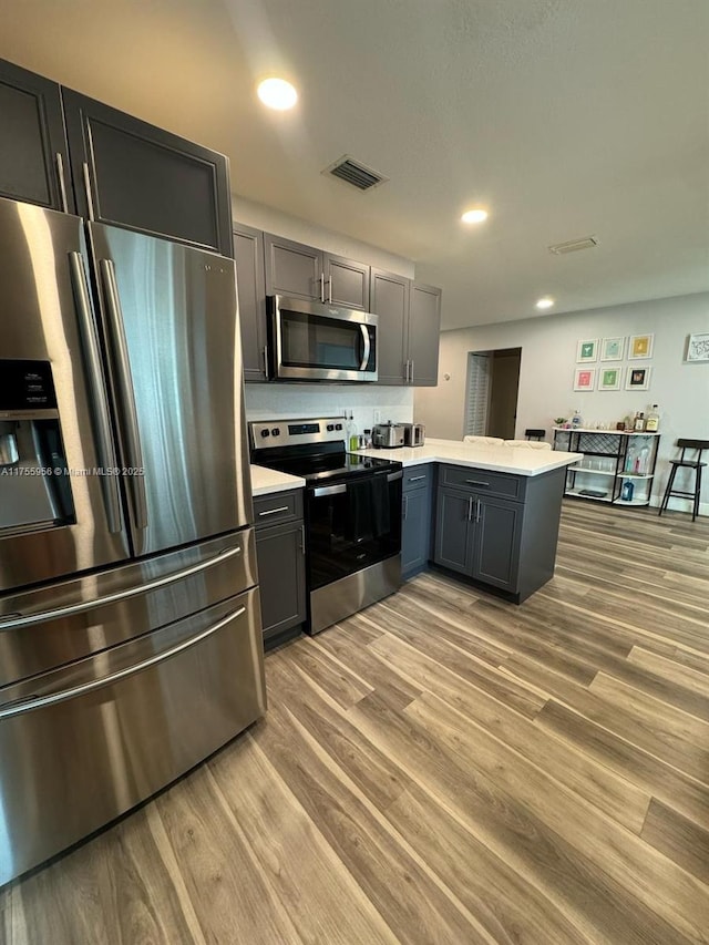 4161 SW 56th Ave, Davie, FL 33314 - kitchen featuring stainless steel appliances, a peninsula, light countertops, light wood-style flooring, and recessed lighting
