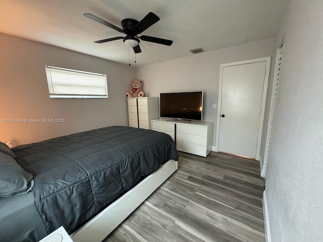 bedroom featuring visible vents, baseboards, ceiling fan, and wood finished floors