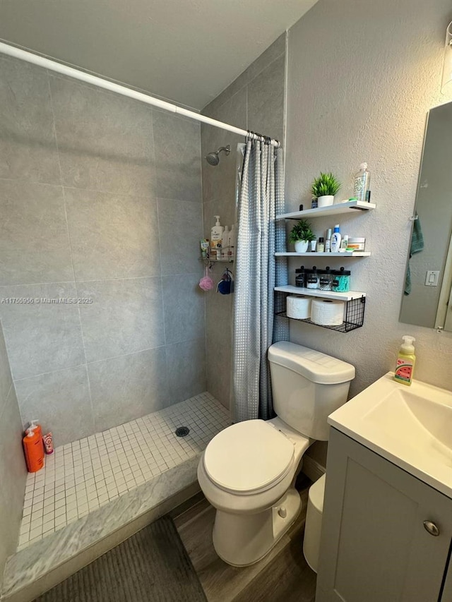 4161 SW 56th Ave, Davie, FL 33314 - bathroom with a tile shower, toilet, wood finished floors, vanity, and a textured wall