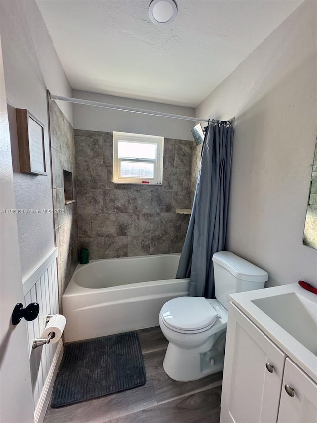 bathroom featuring vanity, wood finished floors, shower / bath combo, wainscoting, and toilet