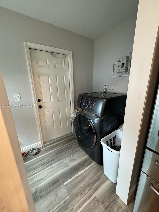 clothes washing area featuring washer / dryer, wood finished floors, and laundry area