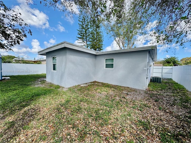 rear view of property with a lawn, a fenced backyard, and stucco siding