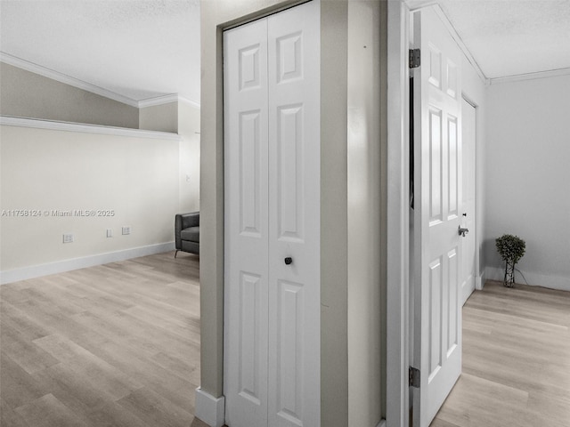 hallway featuring crown molding, a textured ceiling, baseboards, and wood finished floors