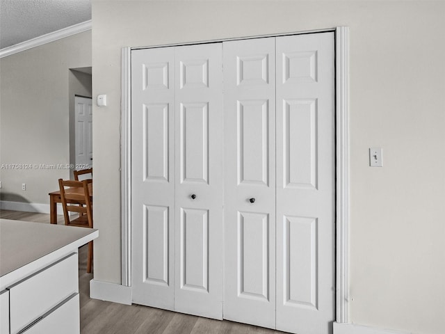 interior details featuring a textured ceiling, ornamental molding, wood finished floors, and baseboards