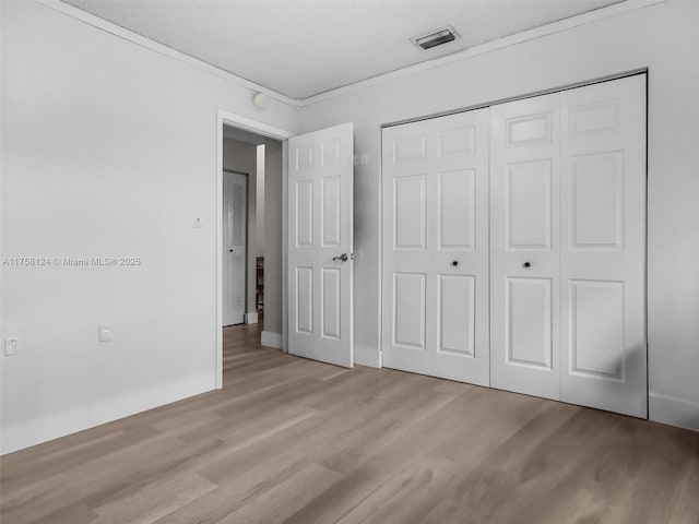 unfurnished bedroom featuring a closet, visible vents, baseboards, and wood finished floors