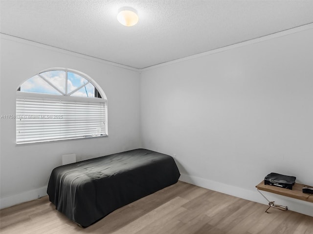 bedroom featuring a textured ceiling, baseboards, and wood finished floors