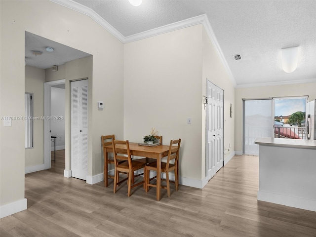 dining area featuring visible vents, crown molding, a textured ceiling, and wood finished floors