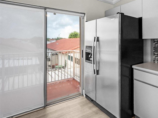 kitchen with light wood-style floors, white cabinets, and stainless steel fridge