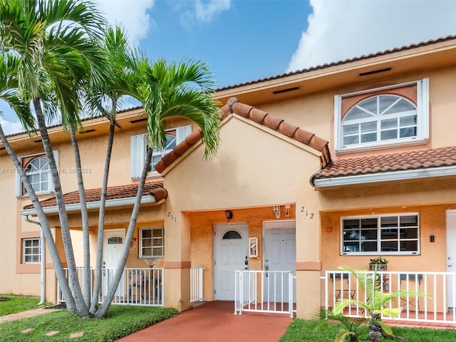 view of front of house featuring a tiled roof, fence, and stucco siding