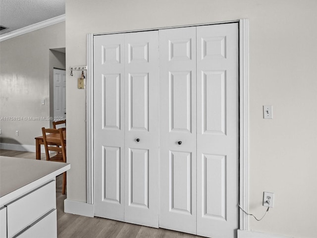 interior details featuring crown molding, visible vents, a textured ceiling, wood finished floors, and baseboards