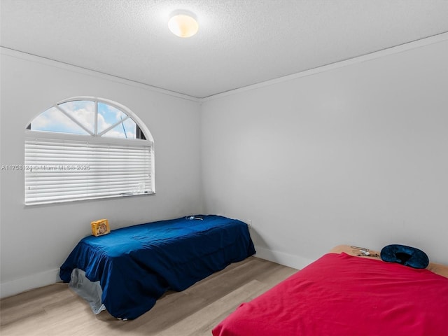 bedroom featuring a textured ceiling, baseboards, and wood finished floors