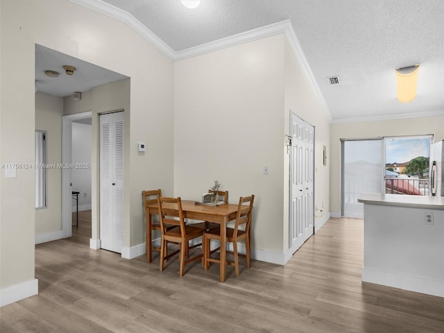 dining room featuring crown molding, a textured ceiling, visible vents, and wood finished floors